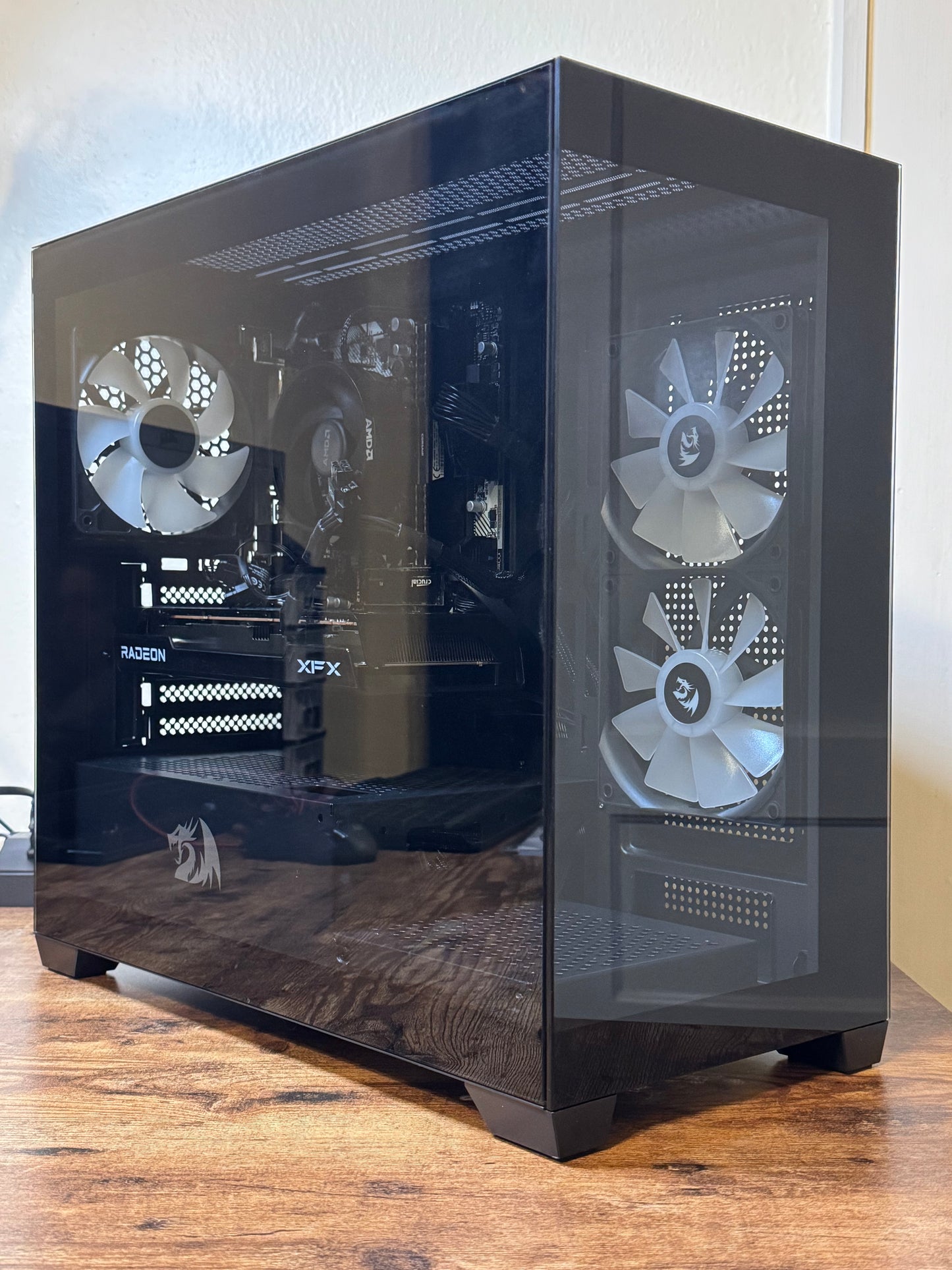 Computer case with three visible fans on a wooden surface